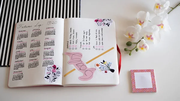 Karlsruhe, Duitsland - 11.11.2019: Tijdschrift, Bullet Journal - Schaafmachine - Notebook - diagonaal bovenaanzicht geïsoleerd op witte achtergrond met orchidee — Stockfoto