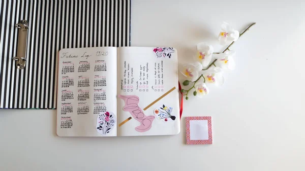 Karlsruhe, Almanya - 11,11.2019: Günlük yaşam tarzı, Bullet Journal - Planer - Notebook - Çapraz üst görünüm orkideyle izole edilmiş