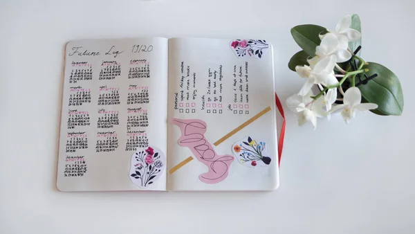 Karlsruhe, Niemcy - 11.11.2019: Dziennik życia, Bullet Journal - Planer - Notebook - widok z góry na białym tle z orchideą — Zdjęcie stockowe