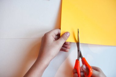 Çocuk beyaz ve renkli kağıtların arka planında renkli kalemlerin uygulamasını keser. Beyaz arka planda renkli bir kalem. Çocuklar bu kalemleri ev etkinliği ve uygulama olarak kullanır..