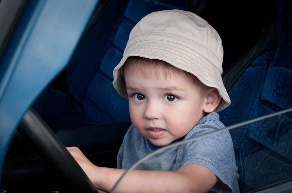 可爱的小男孩牵着方向盘 开着一辆大轿车 饶有兴致地仔细看着窗外 童年的梦想 — 图库照片