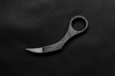 Bıçak Karambit, siyah arka planda metalden yapılmış pençe şeklinde.