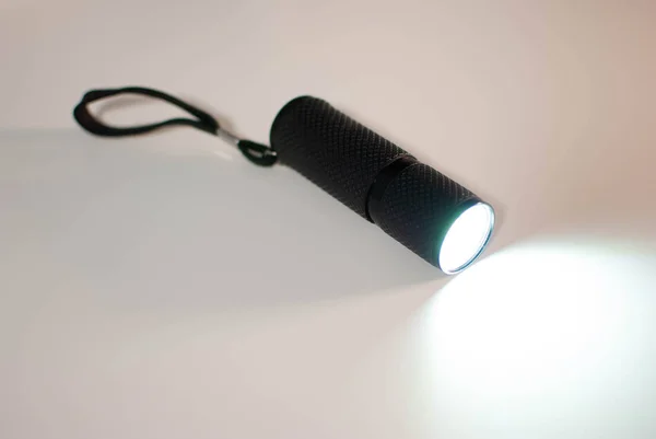 small pocket flashlight light on grey table surface