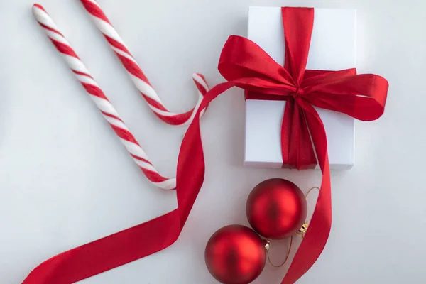 Witte geschenkdoos met rood lint snoepjes en decoraties op witte achtergrond. Bovenaanzicht. Kerstmis en Nieuwjaar vakantie concept. — Stockfoto