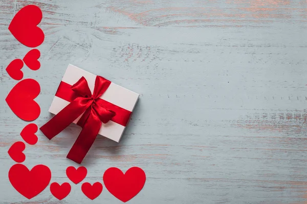 Бумажные черви и белый подарок с красной лентой на светлом окрашенном деревянном фоне. Вид сверху, плоский. День святого Валентина концепция. Copyspace . — стоковое фото