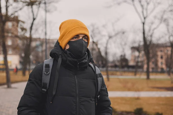 Homme au chapeau orange et masque médical noir dans la rue. Le coronavirus est un virus endémique en Chine. Protection contre la maladie pour les enfants. Concept de sécurité sanitaire . — Photo