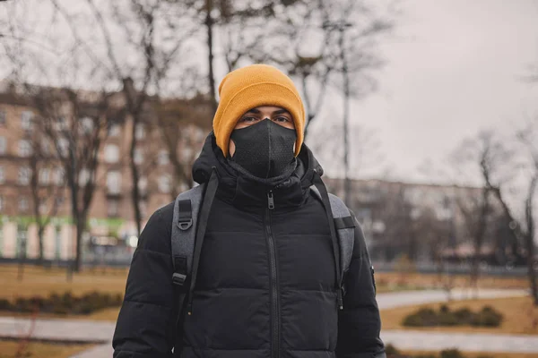 Человек в оранжевой шляпе и черной медицинской маске на улице. Коронавирус - эндемичный вирус в Китае. Защита от болезни для детей. Концепция безопасности . — стоковое фото