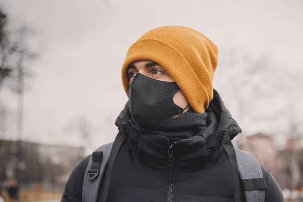 Homme au chapeau orange et masque médical noir dans la rue. Le coronavirus est un virus endémique en Chine. Protection contre la maladie pour les enfants. Concept de sécurité sanitaire . — Photo