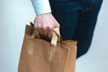 Alışveriş merkezinde elinde malzeme ve kıyafetlerle ekoloji dostu alışveriş çantalarıyla dolaşan şık bir genç adam. Satışlar, indirim konsepti. Mevsimlik satışlar