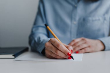 Masadaki belgeleri imzalayan ve düzelten kırmızı tırnaklı kadınların elleri. İş yerinde mavi gömlek giyiyordu. İş, serbest meslek, serbest meslek. Uzaklık işi ve çevrimiçi iş kavramı