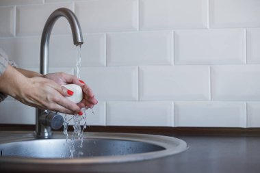 Genç bir kadın Coronavirus enfeksiyonunu önlemek için ellerini sabunla yıkıyor. Hijyeni korumak için kırmızı tırnaklı eller iyice yıkanıyor. Virüs güvenliği. Covid-19 stop konsepti.