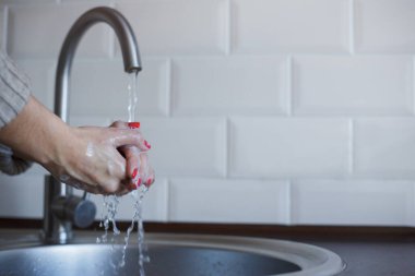 Genç bir kadın Coronavirus enfeksiyonunu önlemek için ellerini sabunla yıkıyor. Hijyeni korumak için kırmızı tırnaklı eller iyice yıkanıyor. Virüs güvenliği. Covid-19 stop konsepti.