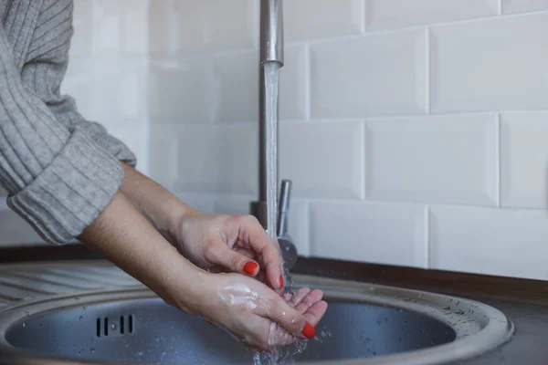 Молодая женщина моет руки с мылом, чтобы предотвратить коронавирусную инфекцию. Руки с красными ногтями тщательно промываются для поддержания гигиены. Безопасность вирусов. Ковид-19 . — стоковое фото