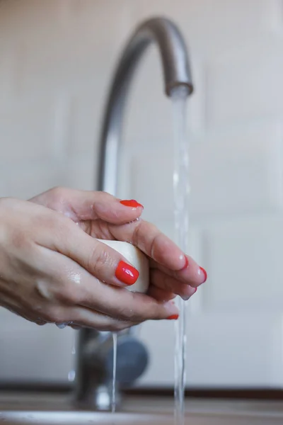 Крупный план молодой женщины моет руки с мылом, чтобы предотвратить коронавирусную инфекцию. Руки с красными ногтями тщательно промываются для поддержания гигиены. Безопасность вирусов. Ковид-19 . — стоковое фото