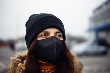 NCov 2019 'dan korunmak için şehir sokaklarında siyah maskeli genç kız pandemik koronavirüs. Cerrahi steril maskeli genç bayana yakın durun. Karantina COVID-19 ve sağlık konsepti