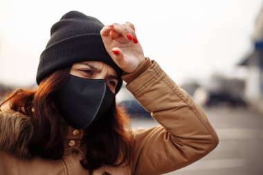Siyah maskeli hasta, maske takan, sıcağa yakalanmış, başı ağrıyan, kötü hisseden hasta bir kız. Birinin yardıma ihtiyacı var..