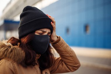 Siyah maskeli hasta, maske takan, sıcağa yakalanmış, başı ağrıyan, kötü hisseden hasta bir kız. Birinin yardıma ihtiyacı var..