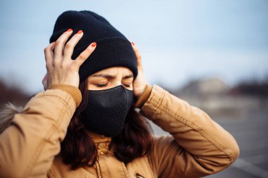 Siyah maskeli hasta, maske takan, sıcağa yakalanmış, başı ağrıyan, kötü hisseden hasta bir kız. Birinin yardıma ihtiyacı var..