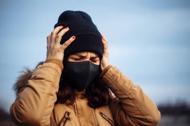 Siyah maskeli hasta, maske takan, sıcağa yakalanmış, başı ağrıyan, kötü hisseden hasta bir kız. Birinin yardıma ihtiyacı var..