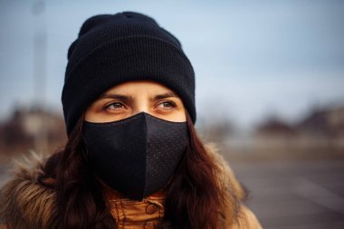 Koruyucu steril tıbbi yüz maskesi takan bir kız sokakta. Kadın, yüz maskesi takıyor, karantina şehrinde virüs, salgın ve salgın hastalıklardan korunuyor. Corona virüsü