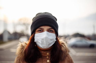 Sokakta maske takan genç bir kız. Solunum koruması. Coronavirus. Tehlikeli bir hastalık. Coronavirus ve tedavisi hakkında makale. Siyah şapkalı bir kadının potansiyeli.