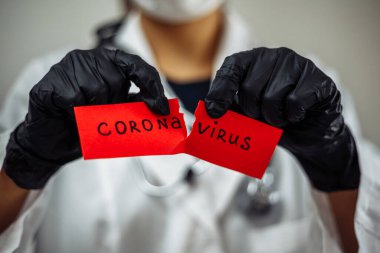 Kan testi tüpü tutan cerrahi maskeli doktor kadın. Gri arka planda izole edilmiş Coronavirus pozitif. Kadın hemşire nCov2019 işareti taşıyor. Covid-19 ve hastalık önleme konsepti