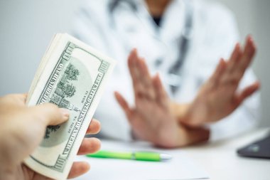 Kadın bir doktorun eli, özel bir tedavi ya da davranış için rüşvet teklifini reddederken kesişti. Hastanelerde yolsuzluk. Bir patent doktora para verir. Coronavirus test ve önleme konsepti