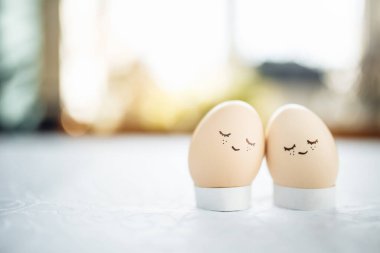İki küçük paskalya yumurtası. Masanın üzerinde izole bir şekilde duran mutlu yüzler çizilmiş. Paskalya tatili süslemeleri ve hazırlık konsepti. Kutsal din günü. Kopyalama alanı, metin için yer