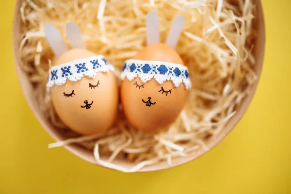 Dwa Jajka Wielkanocne Pomalowanymi Rysunkami Twarzy Królików Uszami Leżącymi Żółtym — Zdjęcie stockowe