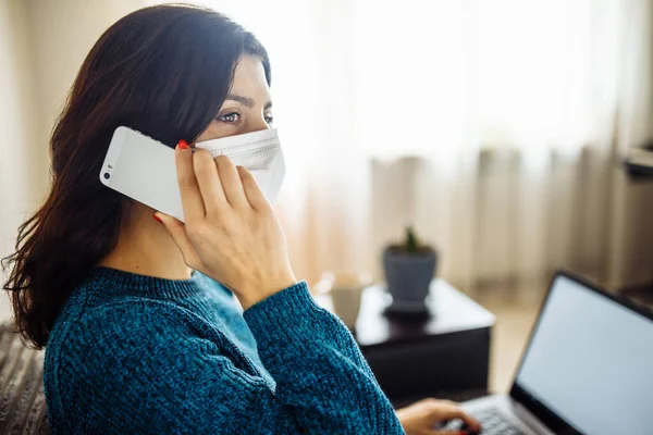İş kadını evde kalır ve koronavirüs epidemisi karantinasında çalışır. Tıbbi maske takan, dizüstü bilgisayarda yazan, cep telefonuyla konuşan bir kadın işçi. Covid-19 pandemisi yayılma önleyici