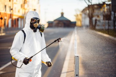 Dezenfeksiyon ekibi çalışanı asfalt çitlerini sterilize bir suyla temizliyor. Koronavirüs enfeksiyonlu yüzeyine püskürtüyor. Covid-19 koruyucu ekipman ve hastalığın yayılmasını önleyecek eylemler