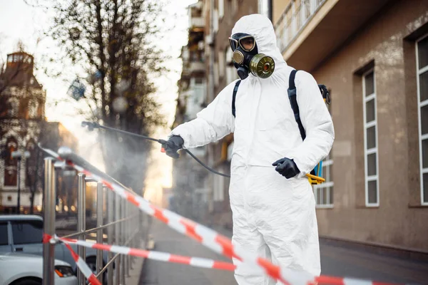 Koruyucu ekipman kullanan bir adam şehirde dezenfektanla dezenfekte ediyor. Coronavirus covid-19 hastalığından dolayı yüzey tedavisi. Beyaz takım elbiseli bir adam sokakları ve rayları dezenfekte ediyor. Virüs salgını