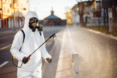 Dezenfeksiyon ekibi çalışanı asfalt çitlerini sterilize bir suyla temizliyor. Koronavirüs enfeksiyonlu yüzeyine püskürtüyor. Covid-19 koruyucu ekipman ve hastalığın yayılmasını önleyecek eylemler