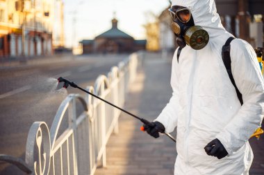 Dezenfeksiyon ekibi çalışanı asfalt çitlerini sterilize bir suyla temizliyor. Koronavirüs enfeksiyonlu yüzeyine püskürtüyor. Covid-19 koruyucu ekipman ve hastalığın yayılmasını önleyecek eylemler