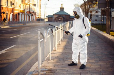 Dezenfeksiyon ekibi çalışanı asfalt çitlerini sterilize bir suyla temizliyor. Koronavirüs enfeksiyonlu yüzeyine püskürtüyor. Covid-19 koruyucu ekipman ve hastalığın yayılmasını önleyecek eylemler