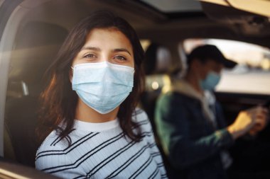 Coronavirus karantinası sırasında araba kullanan bir kız ve bir oğlan tıbbi maskeler takıyor. Salgın covid-19 sırasında güvenli taksi ve sağlık hizmeti. Yolcular için virüs güvenlik kavramı