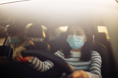 Steril tıbbi maske takan bir kız ve erkek araba kullanıyor. Coronavirus karantina karantinası sırasında yolda kalmış bir yolcusu olan taksi şoförü. Covid-19 kavramının yayılması