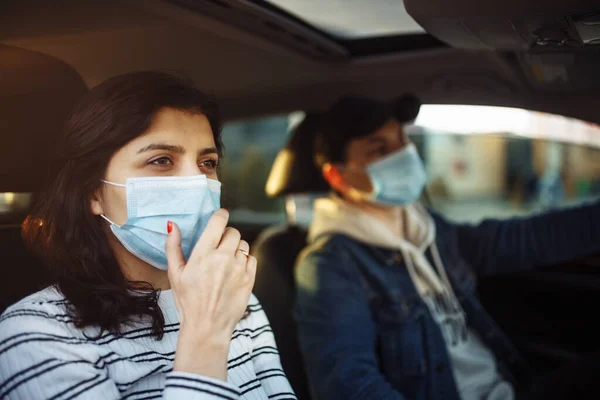 A girl and a boy driving in a car during coronavirus quarantine wearing medical masks. Safe taxi and healthcare during pandemic covid-19. Passangers virus safety concept