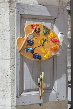 Renkli suluboya tabakları farklı boyutlarda fırçalarla ahşap bir kapıda karıştırıyorum..