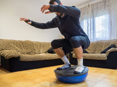 Evde bosu topu üzerinde güç ve denge egzersizleri yapan bir atlet. Spor anlayışı.