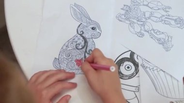 Çocuk bir keçeli kalemle boyama kitabı çiziyor.