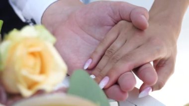 Damat buket arka planda gelinin elini hafifçe okşuyor.