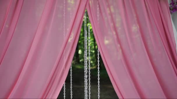 風に揺れる透明なネックレスの美しいピンクの結婚式のアーチ — ストック動画