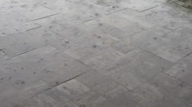 Ilık bahar yağmuru gri granit fayansların üzerine ağır bir şekilde suyla doluyor.