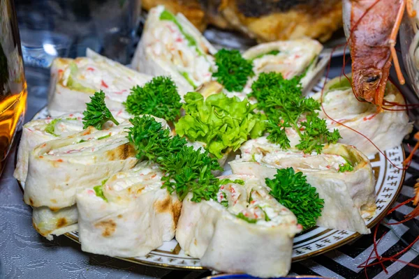 Maydanozla süslenmiş tabakta peynirli pide ve deniz mahsulü.
