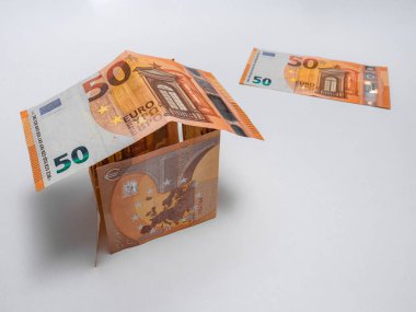 Beyaz arka planda 50 avroluk banknotlar, duvarlar ve çatılardan ve arka planda tek bir biletten oluşan ev