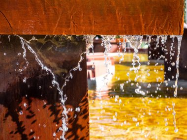 Tuğla kenarları ve metal yapıları olan çeşme su damlası perdeleri yapıyor.