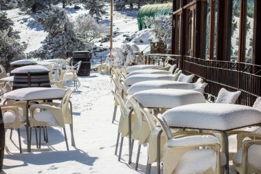 Kar yağdıktan sonra bir barın terasında masalar ve sandalyeler tamamen karla kaplıydı.