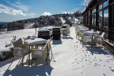 Kar yağdıktan sonra bir barın terasında masalar ve sandalyeler tamamen karla kaplıydı.