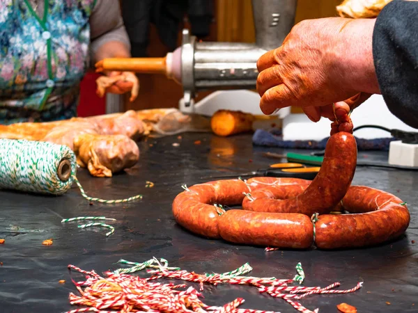 Working women tying red string sausages with rope